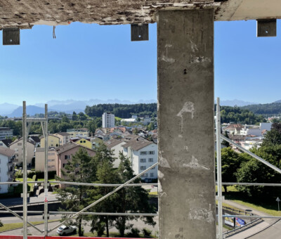 Blick durch Rohbau-Betonstuetzen ueber eine Stadt, Absperrband im Vordergrund
