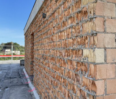 Nahaufnahme einer Backsteinmauer-Ecke mit Parkplatz im Hintergrund