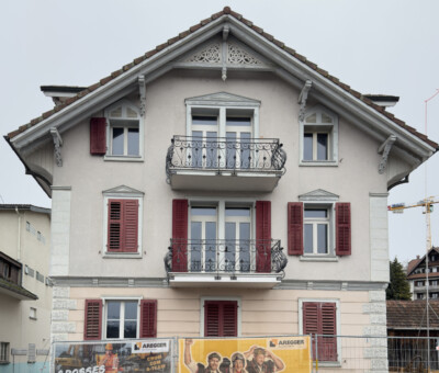 Schweizer Wohn- und Geschaeftshaus mit Balkonen und Ladenbeschriftung im Erdgeschoss