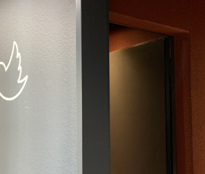 Tuerrahmen-Ecke mit flammenfoermigem LED-Wandlicht, warmes Licht im Hintergrund