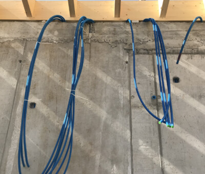 Blaue Kabel haengen an einer Betonwand