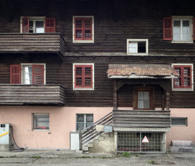 Fassade eines aelteren Wohnhauses mit Holzfensterlaeden und Balkon